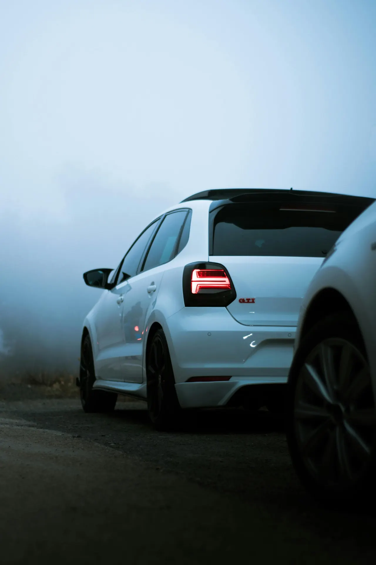 Volkswagen Polo GTI blanche, une compacte du groupe Volkswagen, garée sur une route dans la brume